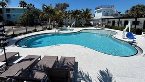 A swimming pool with lounge chairs and a lifeguard stand. - Bridge Street Beach House | Wi-Fi | Center of All (Bradenton Beach)