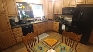 A kitchen with wooden cabinets, a black refrigerator, a stove, and a dining table with chairs.