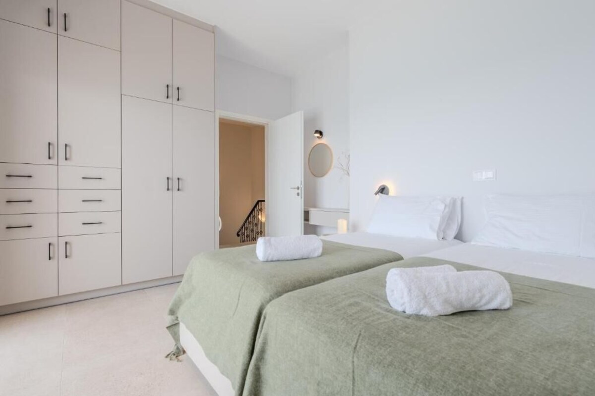 A hotel room with two beds, a large wardrobe, a mirror, and a staircase leading to an outdoor area.