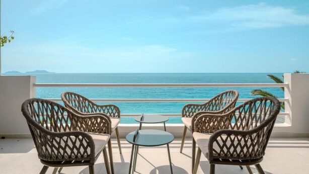 A terrace with wicker chairs and a small table, overlooking a clear blue sea. - East of Preveli Villas (Agios Vasileios)