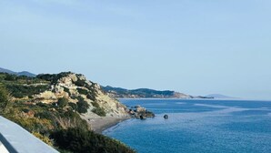 A coastal landscape with a rocky hill, a beach, and calm sea. - East of Preveli Villas (Agios Vasileios)