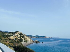 A coastal landscape with a rocky hill, a beach, and calm sea. - East of Preveli Villas (Agios Vasileios)