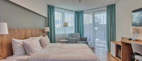 A hotel room with a large bed, a desk, a chair, and a TV.