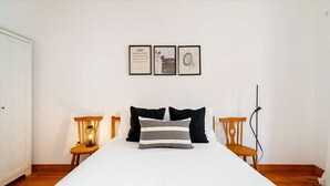 Un dormitorio con una cama grande, dos mesitas de noche, una lámpara y tres cuadros en la pared.