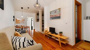 Una sala moderna con un sofá, una mesa de centro de madera, un televisor y un cuadro en la pared.