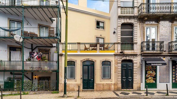 Un edificio con fachada amarilla, puertas verdes y un letrero de restaurante.