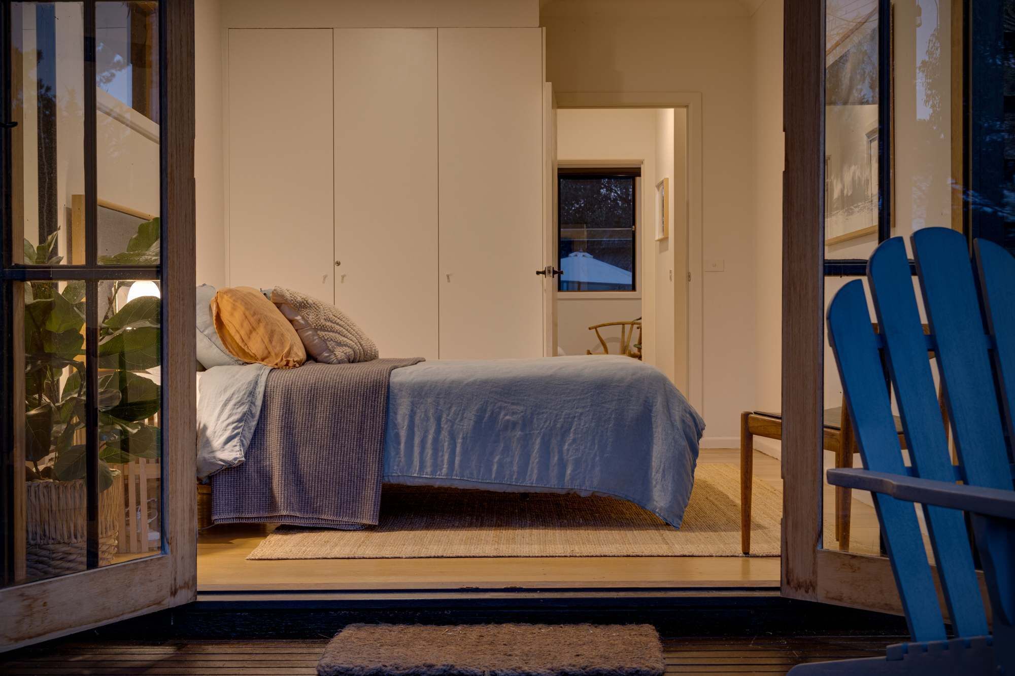 Une chambre à coucher avec un lit, des oreillers, une chaise et une fenêtre.
