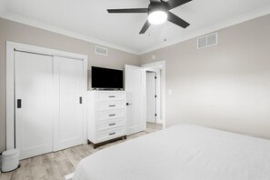 A bedroom with a bed, a wardrobe, a television, and a ceiling fan. - Beach Time Oceanview 3 Bedroom (Pawleys Island)