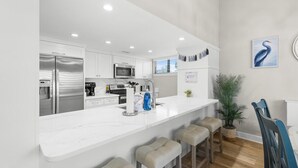 Una cucina moderna con mobili bianchi, elettrodomestici in acciaio inossidabile e un piano di lavoro in marmo.