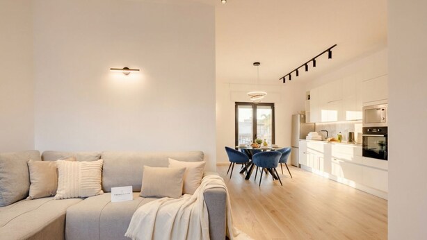 A modern living room with a grey sofa, a dining table with chairs, and a kitchen area with white cabinets and appliances. - MareVista - Private Garden & Parking (Bari)