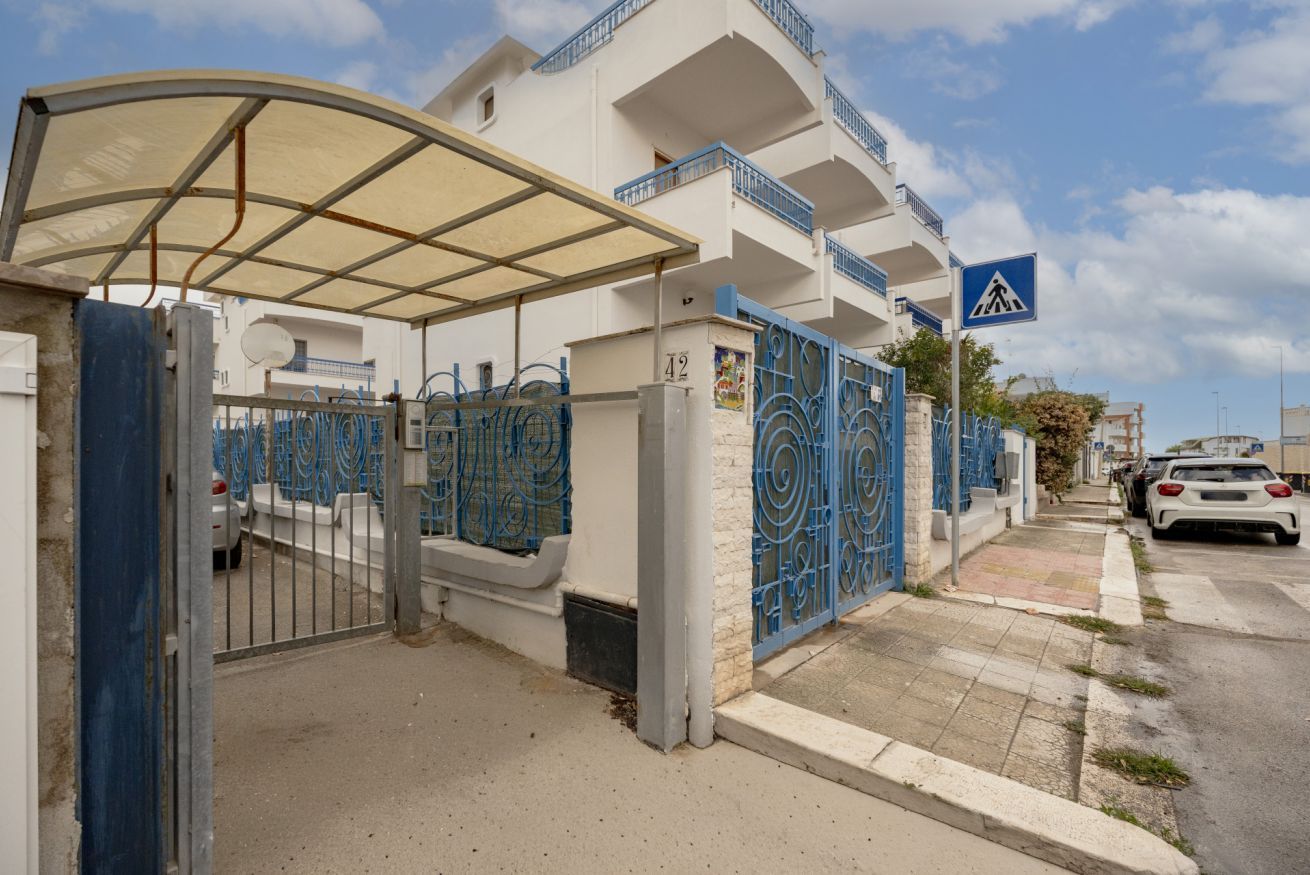 Um edifício residencial com portão fechado, placa de faixa de pedestres e céu claro.