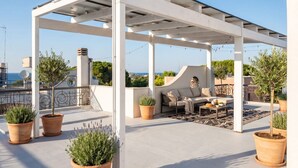 A rooftop terrace with a pergola, seating area, potted plants, and a view of the cityscape. - MareVista - Private Garden & Parking (Bari)