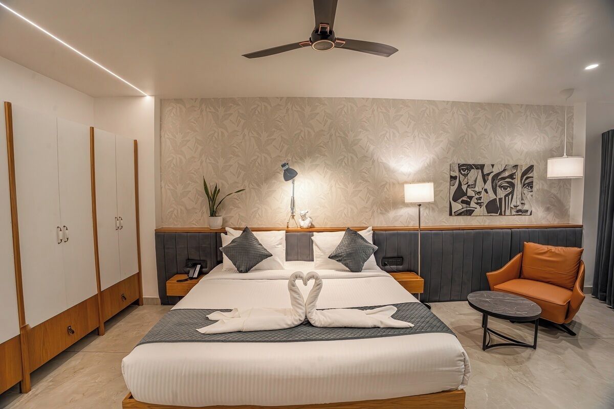 Habitación de hotel con cama, escritorio, silla, ventilador de techo y pared con diseño decorativo.