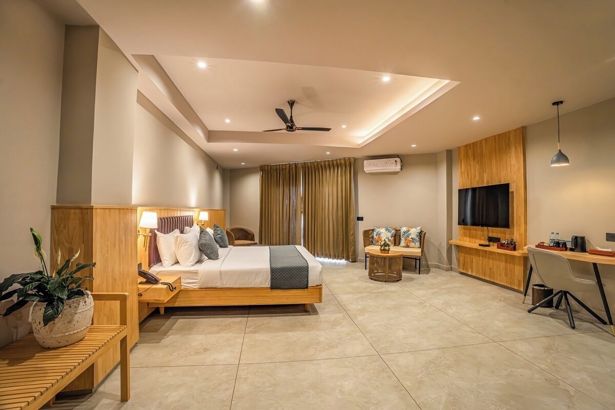 Una habitación de hotel moderna con cama, escritorio, televisor y ventilador de techo.