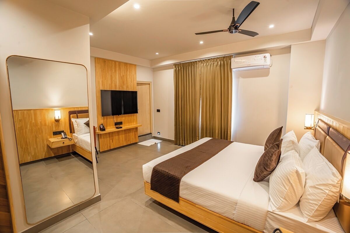 Una habitación de hotel con una cama, televisión, ventilador de techo y aire acondicionado.