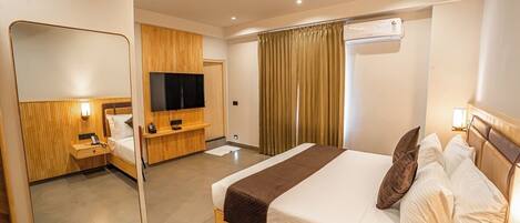 Una habitación de hotel con una cama, televisión, ventilador de techo y aire acondicionado.