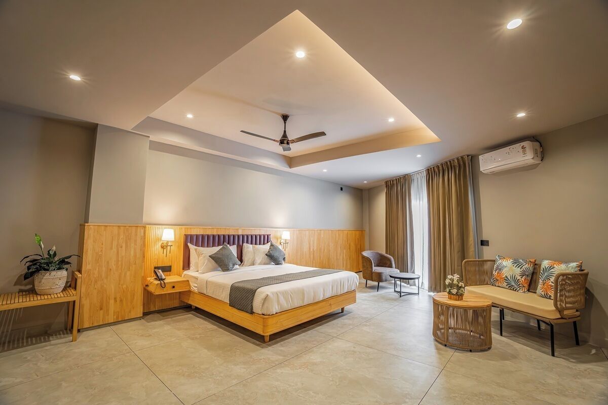 Una habitación de hotel moderna con una cama grande, un escritorio, una silla, un sofá y un ventilador de techo.