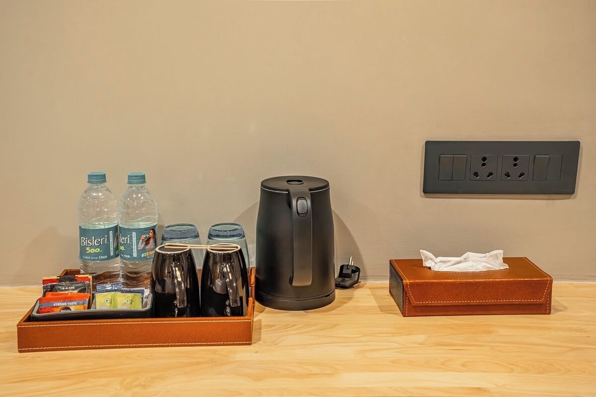 A hotel room with a coffee maker, two water bottles, a tray with tea bags, and a tissue box.