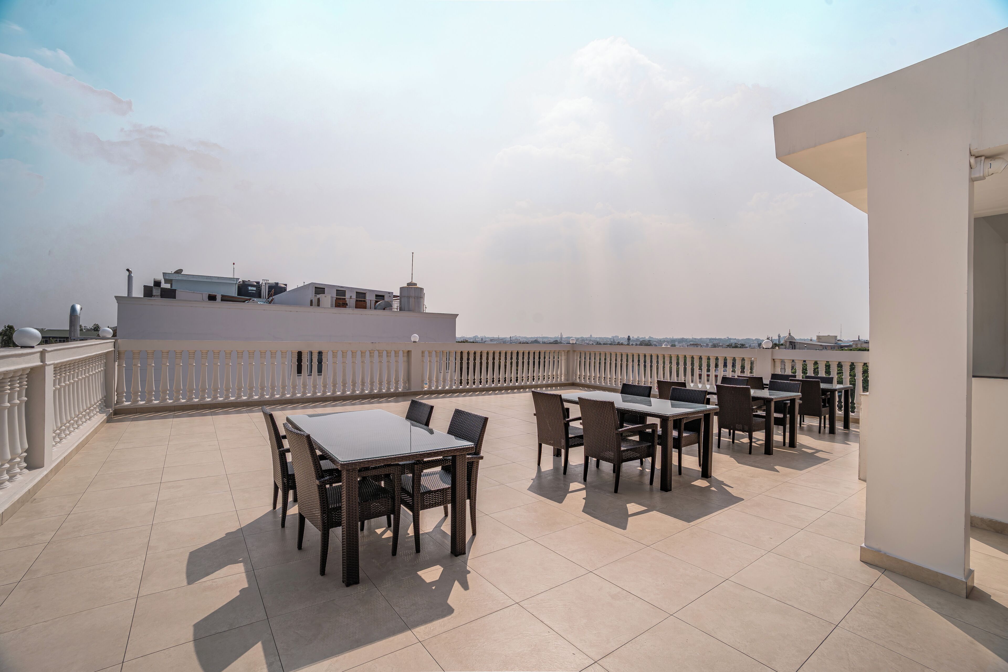 Une terrasse sur le toit, dotée d’un espace extérieur aménagé, d’une rambarde blanche et offrant une vue dégagée sur le panorama urbain.