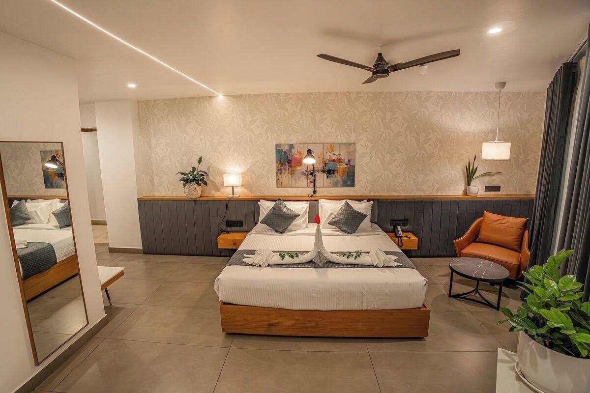 A modern hotel room with a large bed, bedside tables, a desk, a chair, and a ceiling fan.