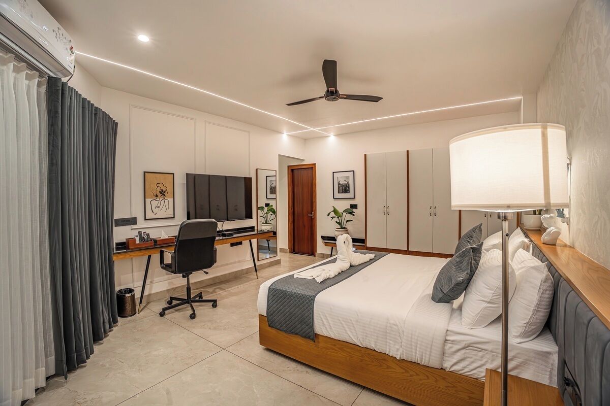 Une chambre d’hôtel équipée d’un lit, d’un bureau, d’une chaise, d’une télévision, d’une armoire et d’un ventilateur de plafond.