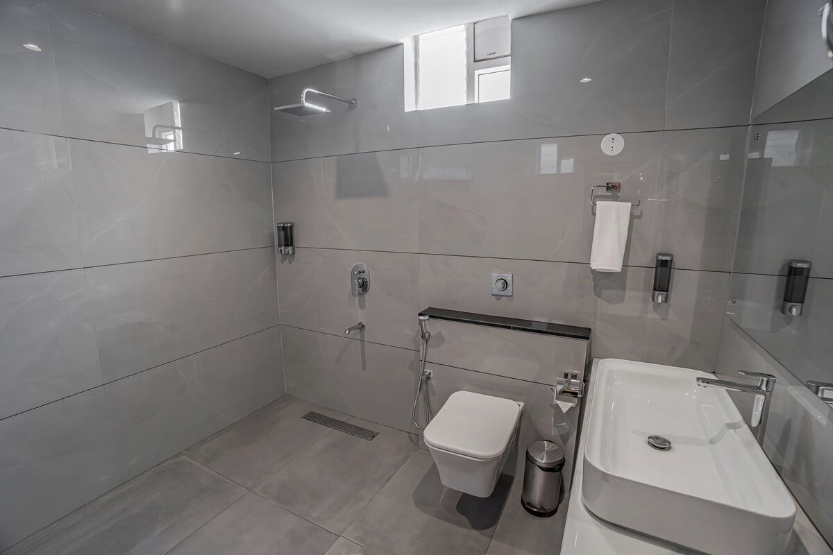 A modern bathroom with a toilet, bidet, and sink, all with chrome fixtures.