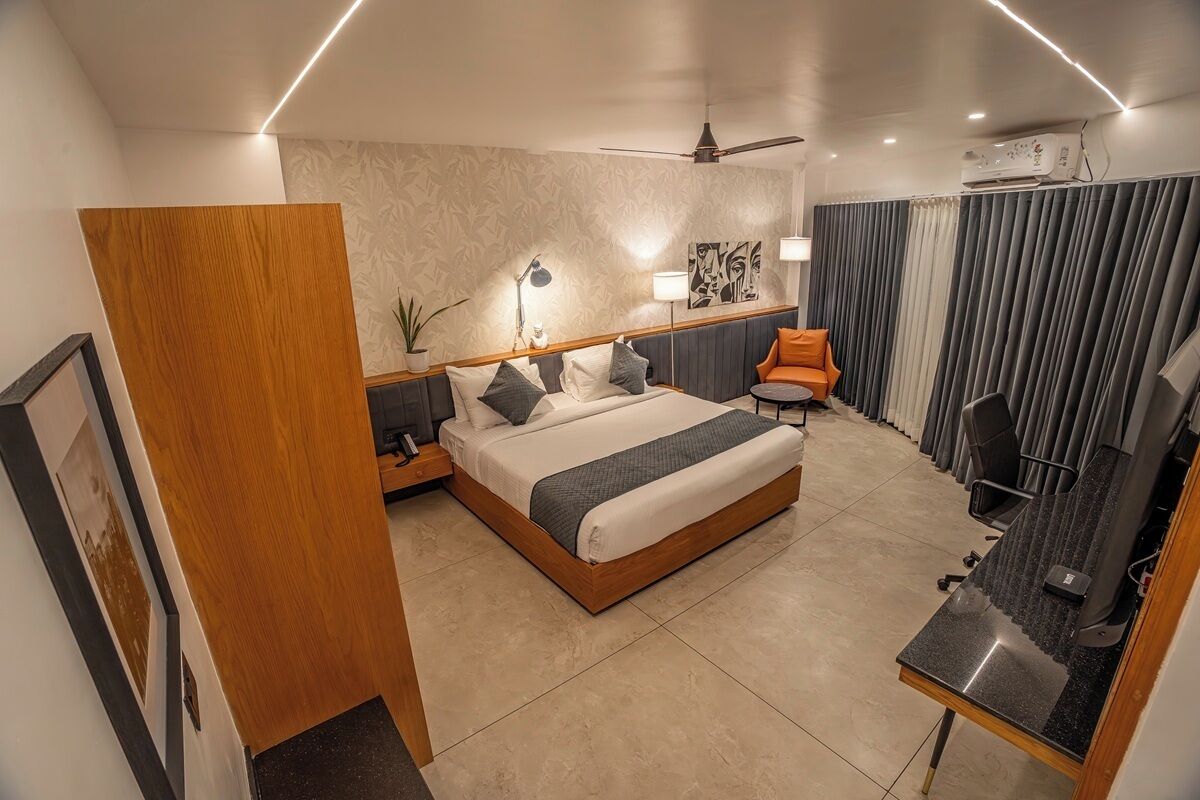A modern hotel room with a large bed, a desk, a chair, a ceiling fan, and a TV.