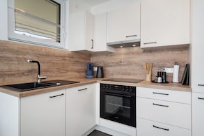 Une cuisine moderne avec un revêtement mural en bois, un four encastré et des meubles de cuisine blancs.