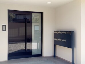 A modern entrance with a glass door, a mail slot, and a dark-colored mailbox.