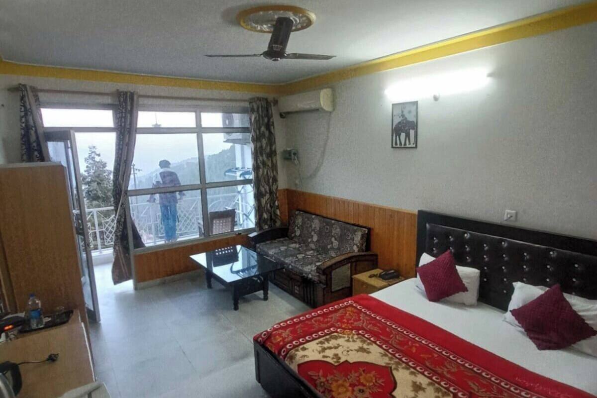 A hotel room with a bed, a sofa, a desk, and a view of the outdoors.