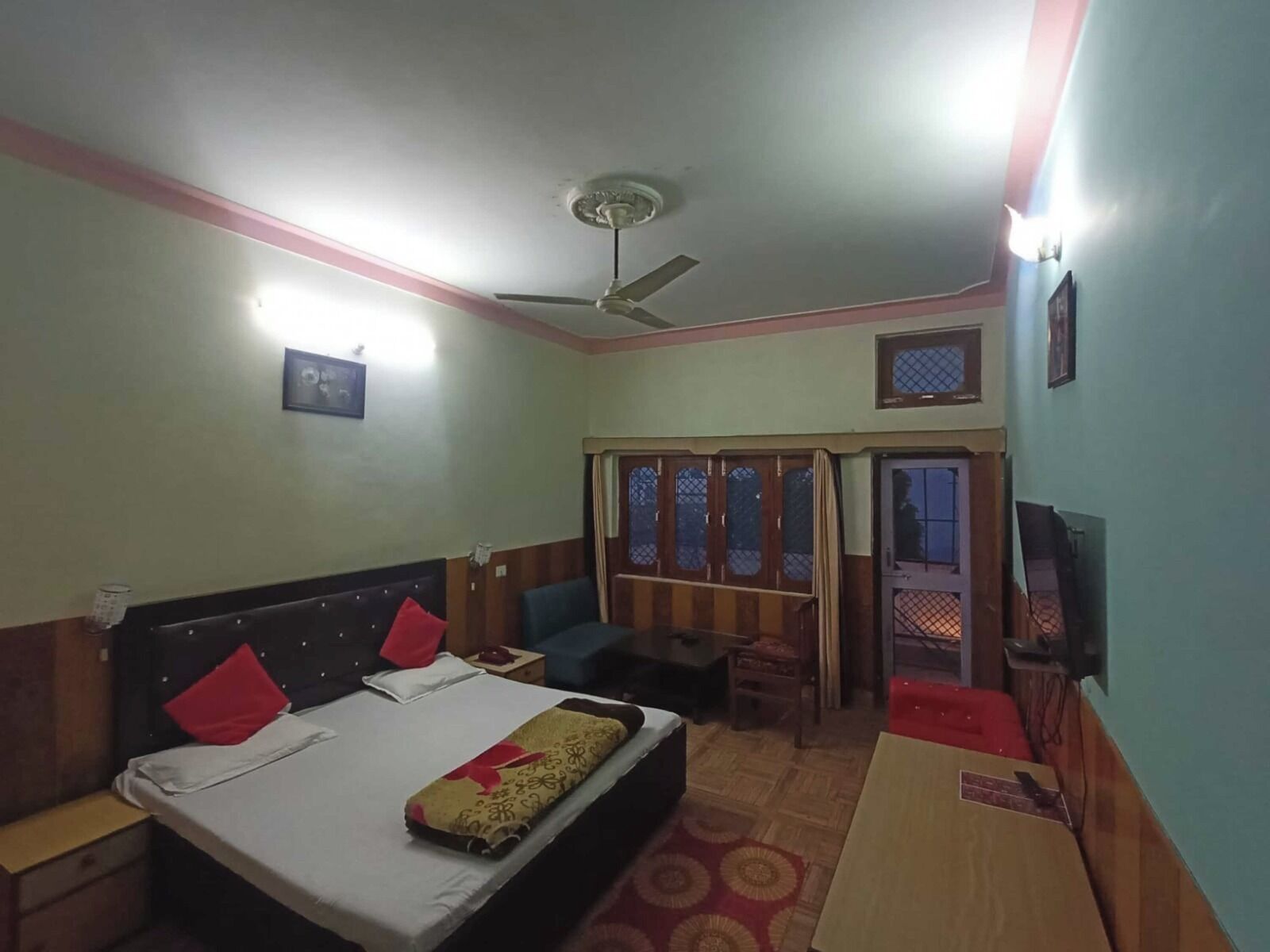 A hotel room with a bed, a desk, a chair, a TV, and a window with curtains.