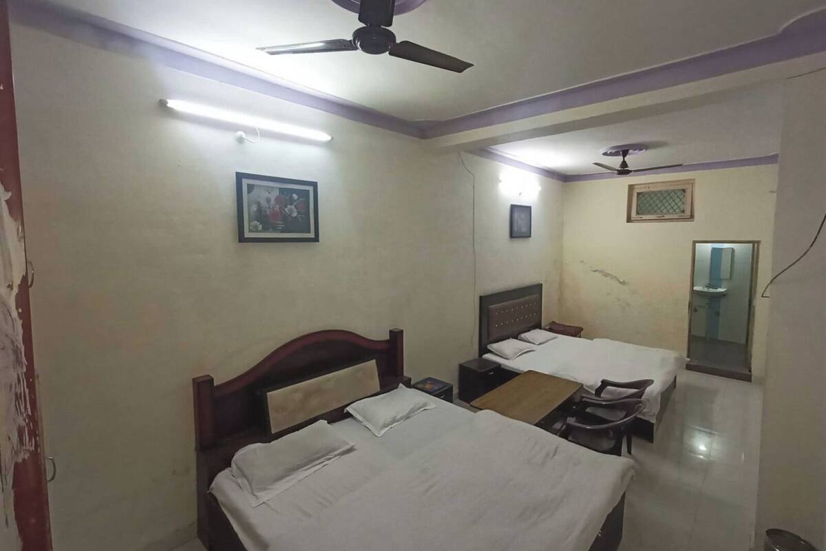A hotel room with two beds, a ceiling fan, a framed picture on the wall, and a bathroom with a mirror and sink.