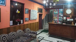 Un vestíbulo con mostrador de recepción, sofás estampados, cuadros enmarcados y una escalera.