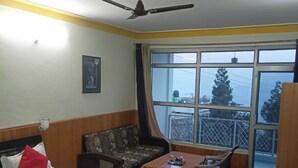 Habitación de hotel con cama, sofá, mesa y balcón con vistas.