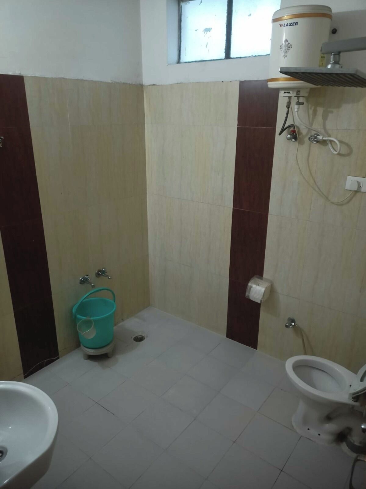 Een kleine badkamer met toilet, wastafel en een boiler aan de muur.