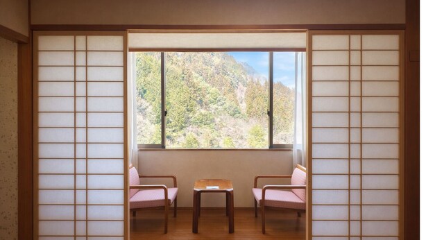 A traditional Japanese room with tatami flooring, a low table, and two cushions. - Hotel Hikyo no yu (Miyoshi)