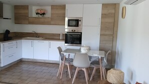 Una cucina moderna con frigorifero, forno a microonde, forno e un tavolo da pranzo con sedie.
