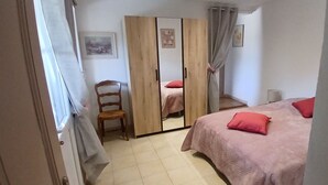 Una camera da letto con un letto, una sedia, un armadio e uno specchio.