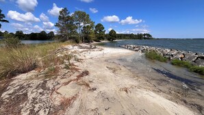 A beach with a clear sky, trees, and a calm lake. - 4BR Riverfront Stilt Home w/ Panoramic Views & Private Beach in Gloucester, VA (Gloucester)