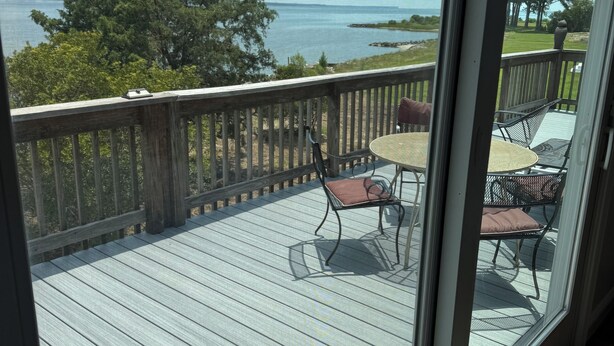 A wooden deck with a table and chairs, overlooking a body of water and trees. - 4BR Riverfront Stilt Home w/ Panoramic Views & Private Beach in Gloucester, VA (Gloucester)