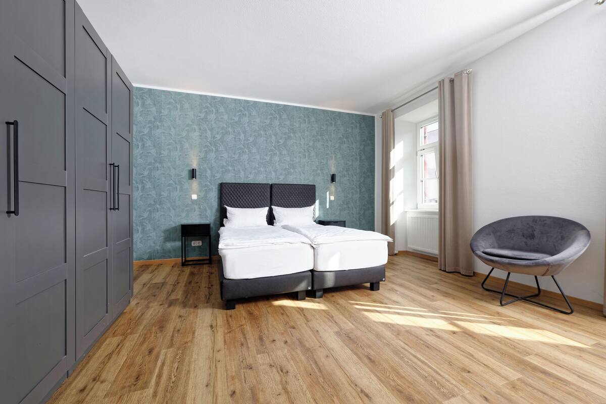 A modern bedroom with a bed, wardrobe, and chair.