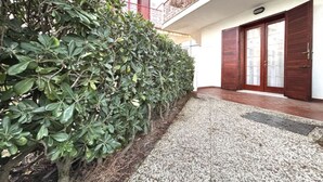 A building with a gravel pathway, a wooden door, and a metal railing on the balcony. - Flat in seafront residence with pool (Rosolina Mare)