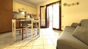 A compact living space with a dining area, kitchen, and a sofa. - Flat in seafront residence with pool (Rosolina Mare)