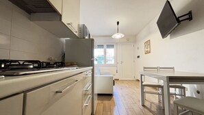 Una cocina con estufa, refrigerador y mesa de comedor con sillas.