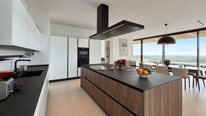 A modern kitchen with a large island, built-in appliances, and a dining area with a view. - Luxury residence with pool - Terra di Bertolino in Menfi - DiCasaInSicilia (Menfi)
