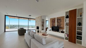 A modern living room with a large sofa, a TV, and a bookshelf. - Luxury residence with pool - Terra di Bertolino in Menfi - DiCasaInSicilia (Menfi)