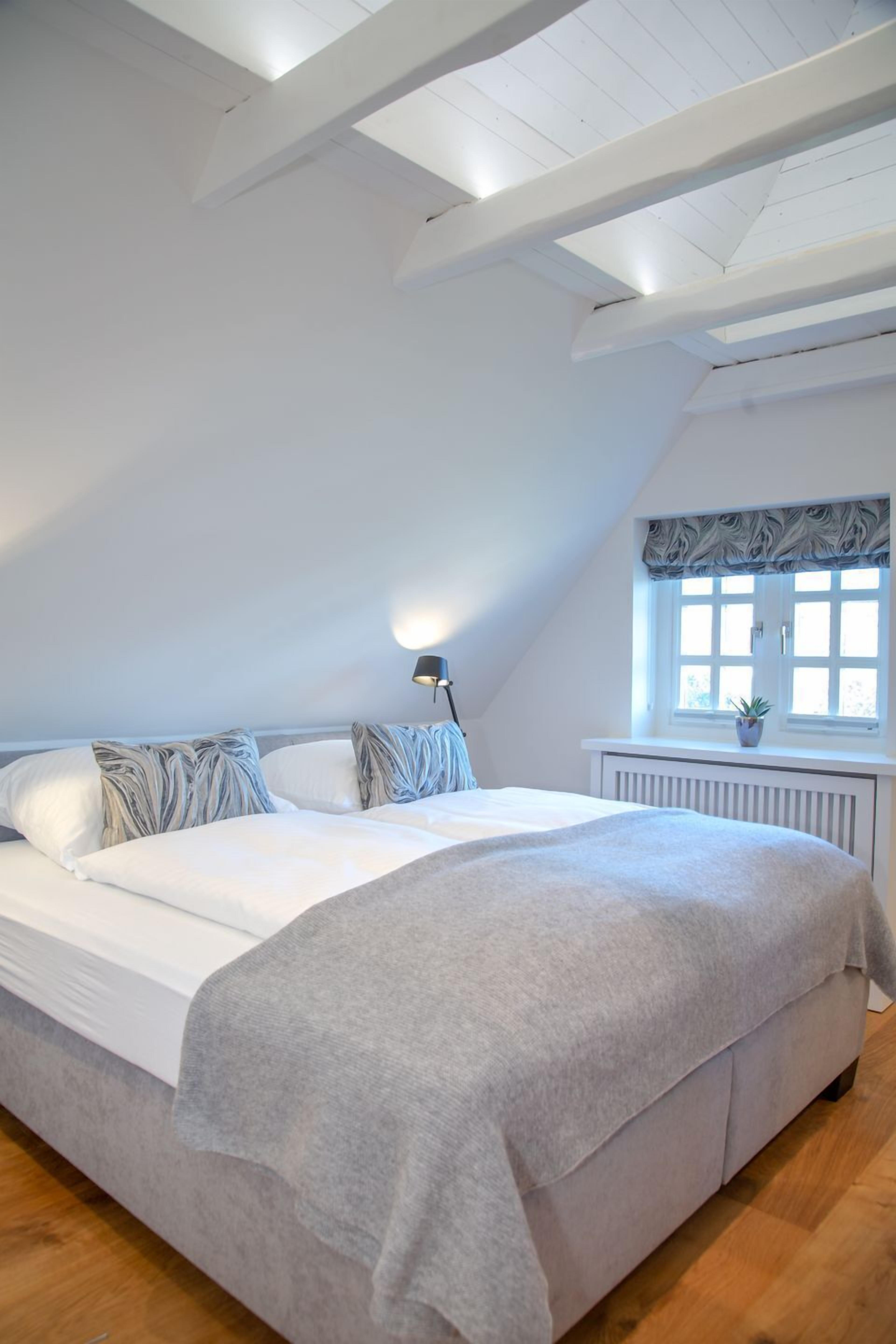 Een slaapkamer met een groot bed, een raam met uitzicht en een plafond met zichtbare balken.