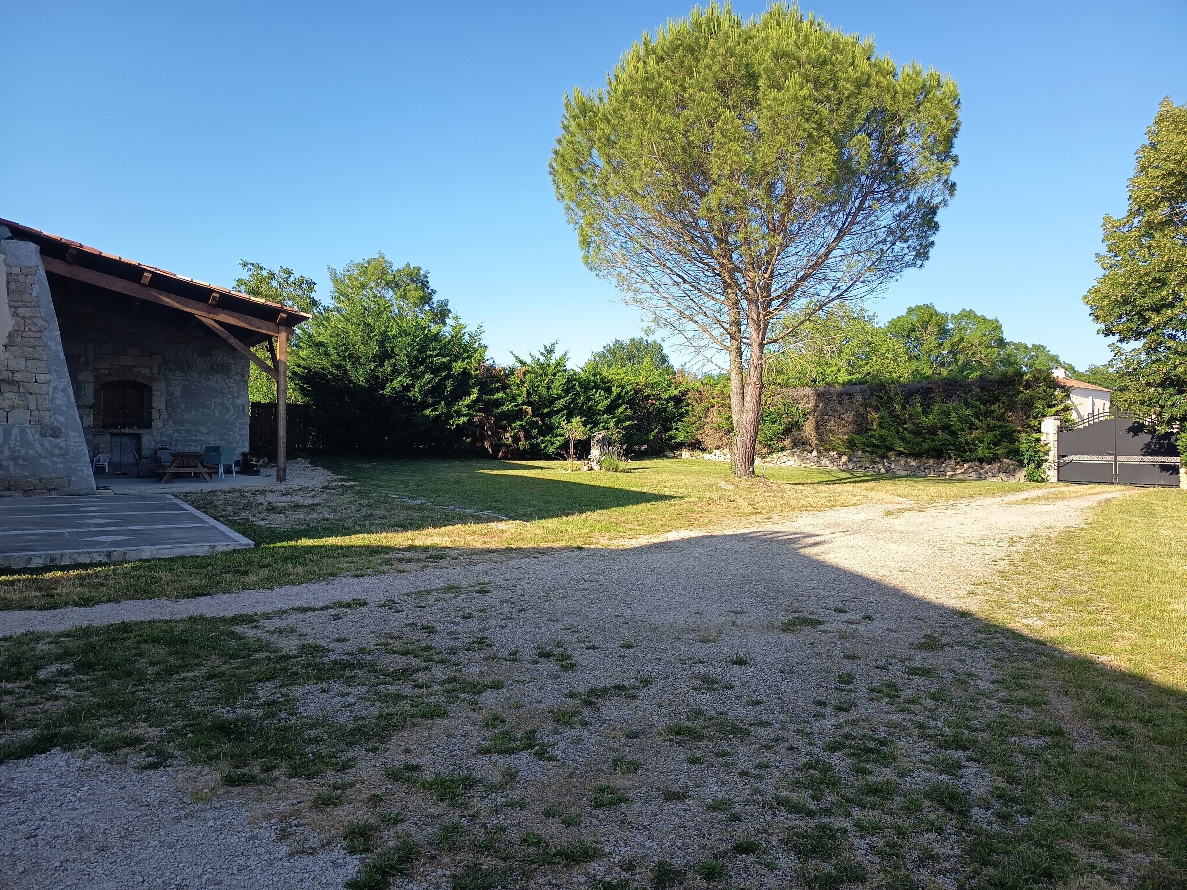 A stone building with a covered patio, a tree, and a gravel path.