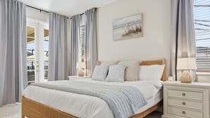 Une chambre à coucher avec un lit en bois, une table de chevet, une lampe et une fenêtre avec des rideaux.