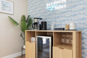 Eine Küchenzeile mit Kaffeemaschine, Mixer und kleinem Kühlschrank.